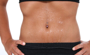 Teen girl's abdomen with belly ring covered in sweat.  Shot with the Canon 20D.