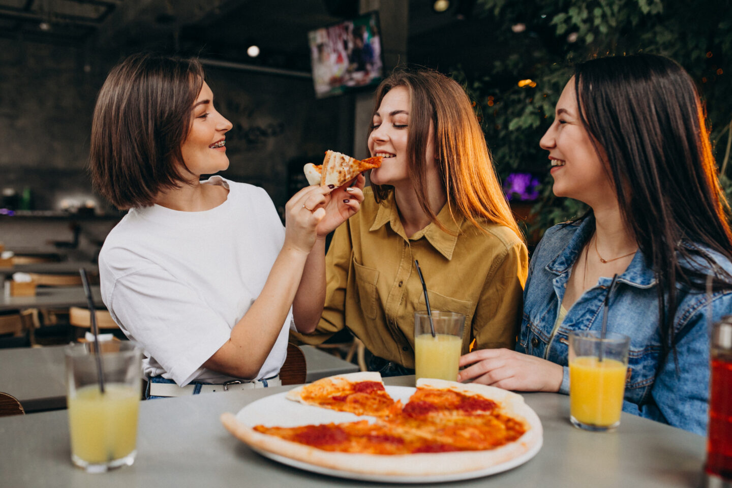 Amigas comiendo pizza en un bar
